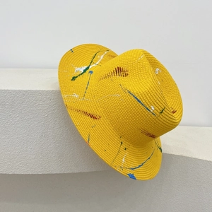 Detail of yellow straw Panama hat featuring unique colorful paint splatter design