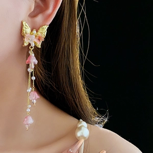 Detailaufnahme von Schmetterling-Ohrringen mit rosa Kristallen und Perlenquasten am Model