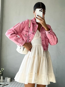 Pink cropped denim jacket paired with a white tiered cotton dress for summer fashion