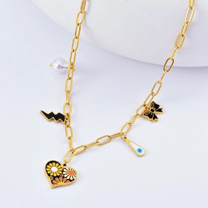 Détail d'un collier doré avec pendentifs perle, cœur et nœud sur une surface blanche pure