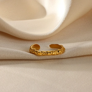 Detail of gold open ring with irregular concave texture on beige silk background