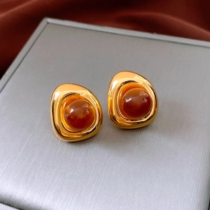 Macro shot of vintage irregular gold stud earrings with red-brown resin center
