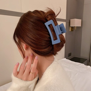 Gros plan d'une grande pince à cheveux carrée bleu mat fixée sur les cheveux longs