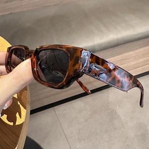 Detail view of tortoiseshell leopard print sunglasses with wide temples and dark lenses