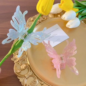 Iridescent butterfly hair claws in blue and pink resin on a vintage gold tray