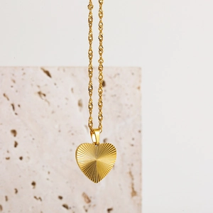 Detailed view of 18k gold heart pendant with radial texture and twisted rope chain necklace