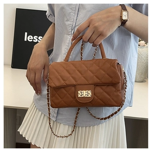 Detailed view of the brown quilted crossbody bag with gold chain strap held by a model