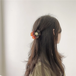 Elegant amber flower hair claw clip with pearl detail shown in a stylish half-up hairstyle