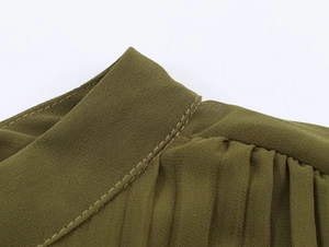 Detailed view of the olive green chiffon dress collar with pleats and metal trim