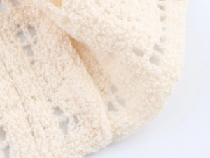 Close-up of cream hollow knit vest showing intricate crochet texture and floral patterns