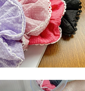 Macro detail of textured scrunchie fabric with lace trim in purple, pink, red, and black