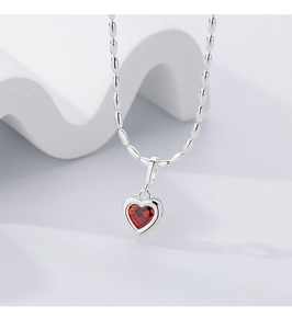Close-up of heart-shaped 925 sterling silver necklace with a bright red gemstone center