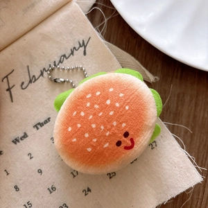 Close-up of plush burger keychain with smiling face and green lettuce detail