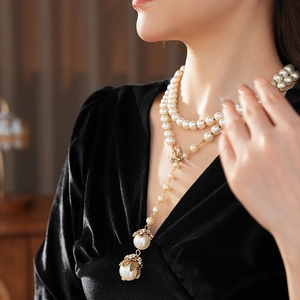 Detail of layered pearl necklace with floral pendant on elegant woman neck