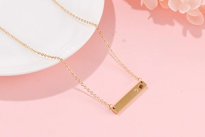 Macro shot of gold bar pendant necklace with heart engraving and amber gemstone inlay