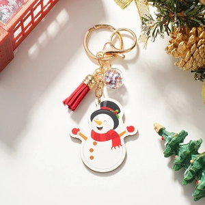 Close-up of cute Christmas snowman keychain with red tassel and starry ball details