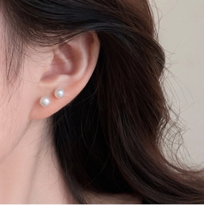Close-up of minimalist white freshwater pearl stud earrings on a model's ear