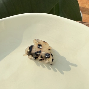 Close-up of tortoise shell mini hair claw with sparkling rhinestones in a ceramic bowl