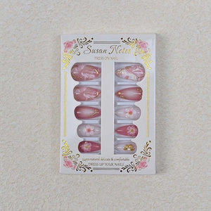 Detail of almond press-on nails with 3D floral carvings and gold gilded marble texture