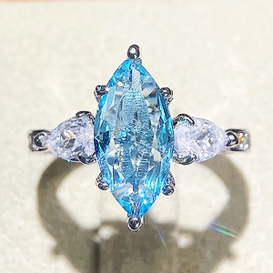 Macro shot of marquise-cut light blue stone with pear-shaped side stones on a silver ring