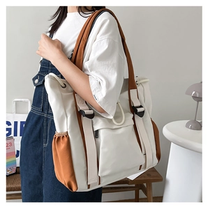Side view of a large canvas tote bag in beige and brown, styled in a minimalist room