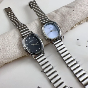Flat lay of oval women's watches with black and light blue dials on silver metal bands