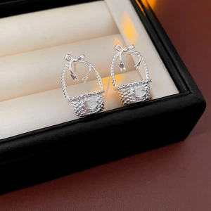 Detailed close-up of silver bow basket earrings with intricate metallic finish