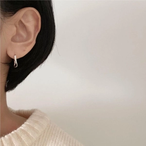 Detail of twisted silver hoop earrings worn with a cozy minimalist knit sweater