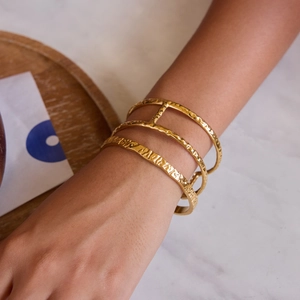 Detailed view of layered 18K gold stainless steel cuff with hammered texture on model