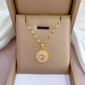 Gros plan du collier en or avec pierre de coeur rose et diamants dans un coffret à bijoux