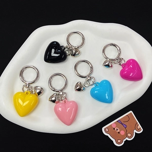 Colorful resin heart keychains in black pink blue and yellow on white ceramic tray
