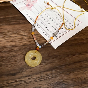 Détail du pendentif en agate sculptée avec cordon en soie et perles au style ethnique