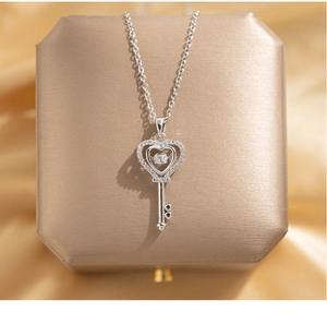 Détail du pendentif clé en argent avec cœur battant et pierres sur soie