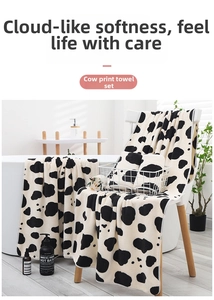 Detailed view of plush cow print coral fleece towel set draped on a white chair