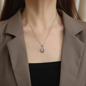 Detail of pink oval cat-eye stone necklace with twisted metal border on silver chain