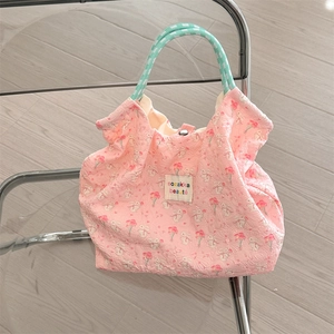 Detail of pink quilted tote bag with rabbit pattern and braided rope handles on a chair