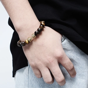 Bracelet en perles d'œil de tigre et agate avec haltère doré porté au poignet homme