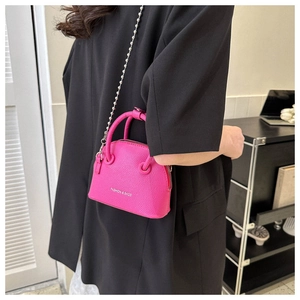 Detail of fuchsia shell bag featuring lychee grain leather texture and beaded chain strap