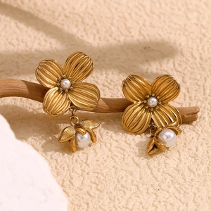 Vintage 18K gold plated flower earrings with white pearl dangles on a wooden branch