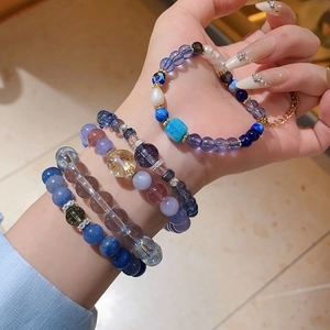 Close-up of stacked blue zircon and crystal beaded bracelets with elegant gold metal accents