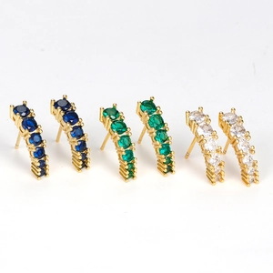 Detailed close-up of curved gold earrings set with blue, green, and white gemstones