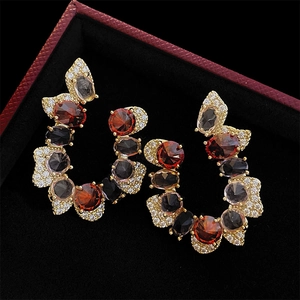 Macro detail of vintage C-shaped earrings with red and black stones in gold setting
