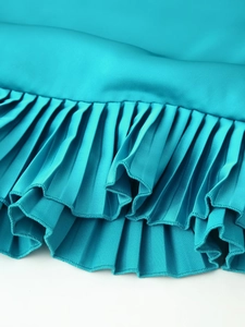 Detail of teal green pleated satin fabric with high-quality edge overlock stitching