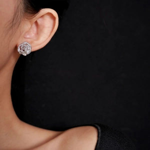 Élégant clip d'oreille camélia argenté avec zircons pavés porté par un mannequin