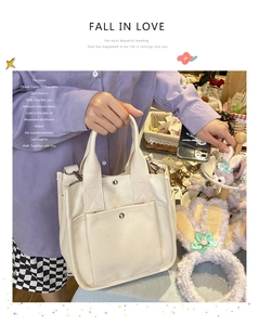 Detailed close-up of a beige canvas handbag with front pocket and silver hardware detail