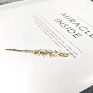 Elegant gold star hair clip with rhinestones placed on an open book, french style hairpin