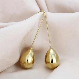 Elegant gold-tone teardrop earrings with long hooks on a soft beige silk background
