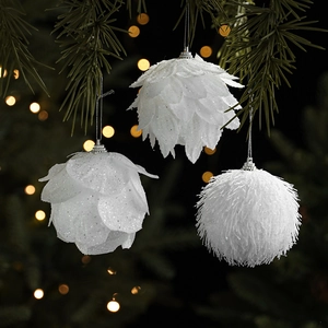 White glitter pine cone and plush Christmas ball ornaments hanging on pine branches