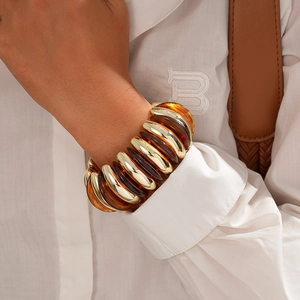 Detail of bohemian acrylic and gold metal elastic bracelet worn on wrist with shirt