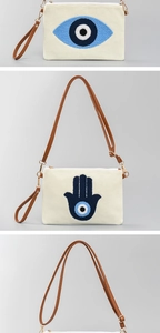 Detail der gewebten Canvas-Clutch mit Evil Eye und Hamsa Stickerei und braunem Lederriemen